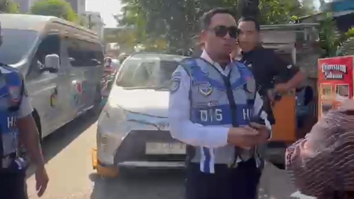 Petugas Dishub Makassar menertibkan 17 mobil yang parkir di bahu jalan. Seorang pengemudi protes saat mobilnya digembok