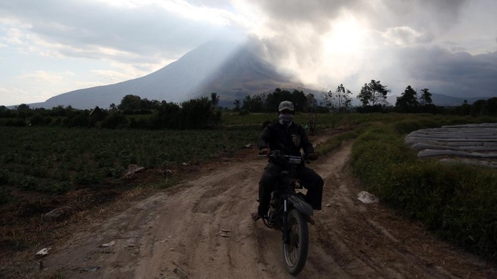 Warga mengendarai sepeda motor dengan latar Gunung Sinabung yang erupsi di Kecamatan Naman Teran, Kabupaten Karo, Sumatera Utara, Senin (31/8/2026). Gunung Sinabung mengalami erupsi dengan tinggi kolom abu mencapai 3.500 meter atau sekitar 5.960 meter di atas permukaan laut.ANTARA FOTO/Yudi Manar