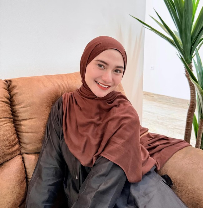 Paduan santai terpancar dari pilihan kemeja berpotongan longgar warna gelap yang dipadukan dengan pashmina cokelat. Lilitan hijab pashmina yang simpel memberikan kesan effortless yang nyaman dipakai sehari-hari. Foto: Dok. Instagram @enazirashf_.