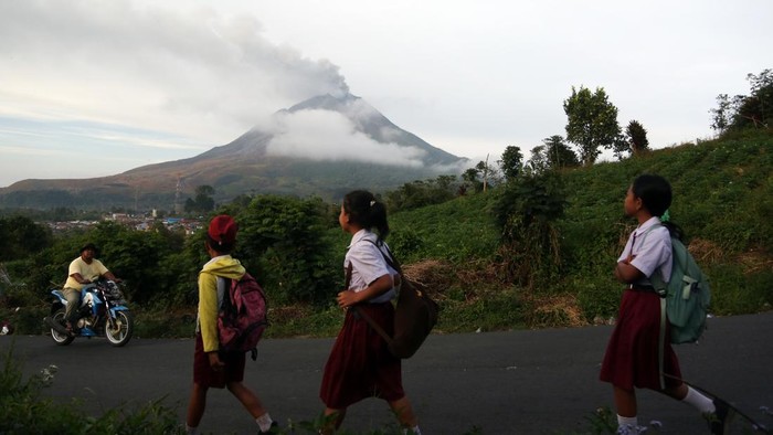 Siswa berangkat sekolah saat erupsi Gunung Sinabung di Desa Kutarayat, Kecamatan Naman Teran, Kabupaten Karo, Sumatera Utara, Selasa (1/9/2026). Pusat Vulcanologi dan Mitigasi Bencana Geologi menyampaikan bahwa tingkat aktivitas Gunung Sinabung berada di level III atau siaga sehingga masyarakat dan wisatawan agar tidak melakukan aktivitas di desa yang sudah direlokasi.ANTARA FOTO/Yudi Manar/YU