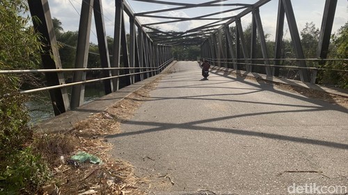 Warga nekat melintasi Jembatan Bakong, Lombok Barat, yang rusak menggunakan kendaraan roda dua, Selasa (1/9/2026). (Foto : M. Zahiruddin/detikBali)