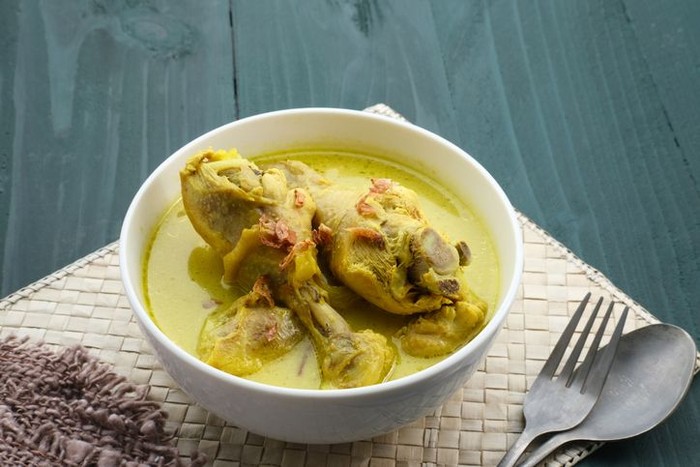 Opor Ayam, Indonesian traditional food in white bowl on grey background. Opor made from chicken cooked with coconut milk and spices. Its served to celebrate Eid Adha and Eid Fitr.