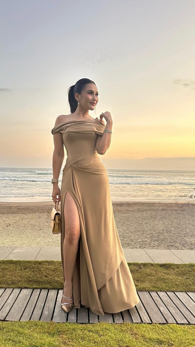 Ayu Ting Ting mengenakan gaun rancangan Rika Wirtjes yang menjuntai menyentuh lantai. Penampilannya semakin menawan dengan aksen draperi dan slit pada bagian roknya. Foto: Dok. Instagram Ayu Ting Ting