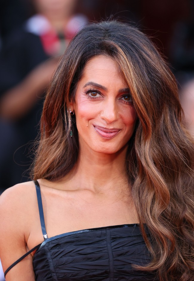 Pengacara hak asasi manusia kelahiran Lebanon ini tampil dengan gaya riasan khasnya dan membiarkan rambut cokelat panjangnya terurai. Rambutnya ditata dengan belahan samping dan gelombang, menciptakan tampilan Oly Hollywood.Foto: Dok. Getty Images, AFP