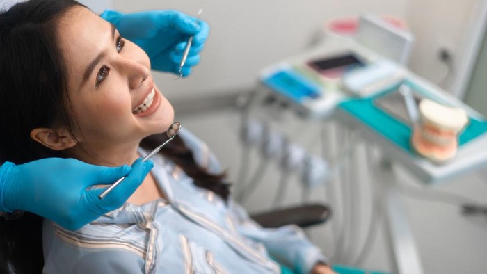 Young happy asian woman during dental procedure at dentists office.