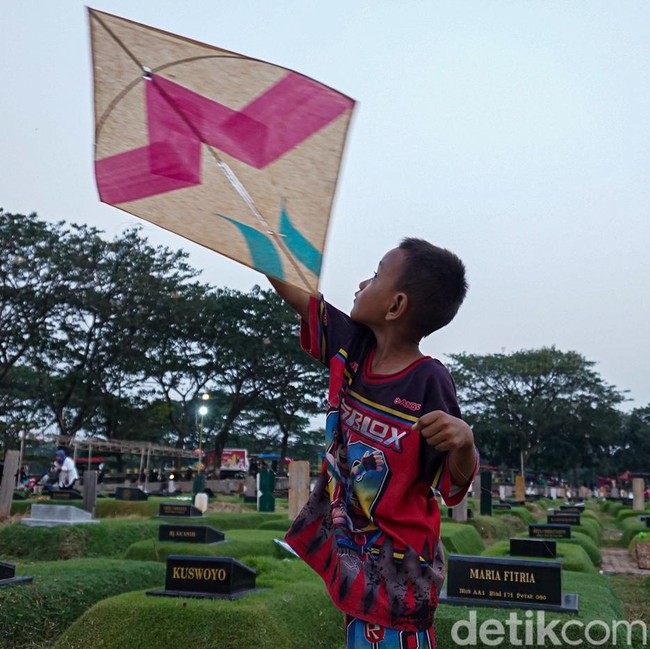 Di Sela Makam, Anak-anak Tetap Riang Bermain Layangan di TPU Tanah Kusir