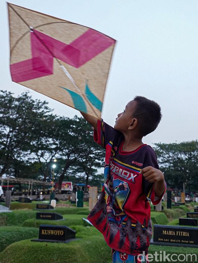 Di Sela Makam, Anak-anak Tetap Riang Bermain Layangan di TPU Tanah Kusir