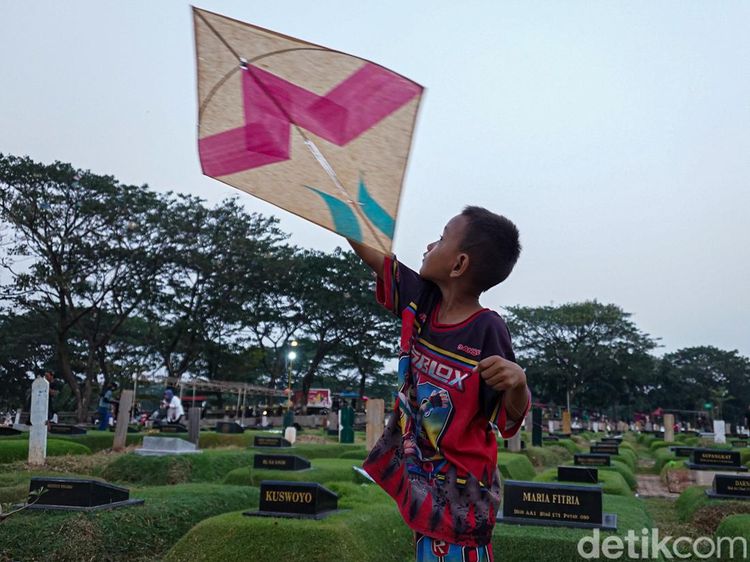 Di Sela Makam, Anak-anak Tetap Riang Bermain Layangan di TPU Tanah Kusir
