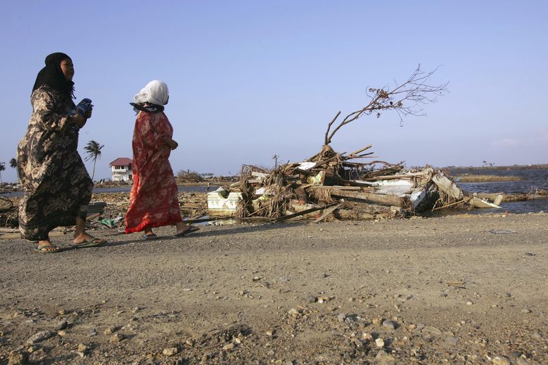 BANDA ACEH, INDONESIA - JANUARY 21: Two women walk through an area destroyed by the tsunami January 21, 2005 in Banda Aceh, Indonesia. More than three weeks after the tsunami, thousands of people are still being pulled from the rubble in Aceh. The province of Aceh, one of the worst hit regions of the 9.0 earthquake and subsequent Tsunami, lost well over 50,000 people.  (Photo by Spencer Platt/Getty Images)