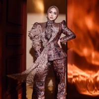 Ricis mengenakan setelan bernuansa cokelat maroon, dusty rose, dan keemasan dengan motif yang terlihat mewah. Atasannya berpotongan peplum, sehingga bagian pinggang tampak lebih tegas sementara bagian bawah sedikit mengembang. Foto: Instagram/@riaricis1795