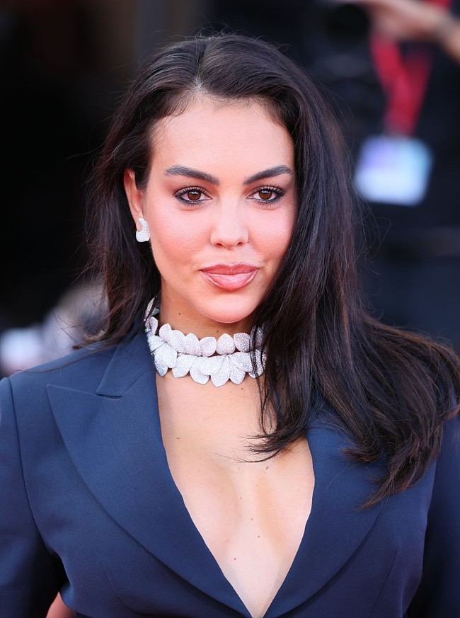 Georgina memberi sentuhan glamor lewat aksesori yang mencuri perhatian. Ia mengenakan kalung bertingkat dua, anting berukuran besar, serta beberapa cincin berbentuk bulan sabit. Foto: FilmMagic/JB Lacroix
