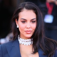 Georgina memberi sentuhan glamor lewat aksesori yang mencuri perhatian. Ia mengenakan kalung bertingkat dua, anting berukuran besar, serta beberapa cincin berbentuk bulan sabit. Foto: FilmMagic/JB Lacroix