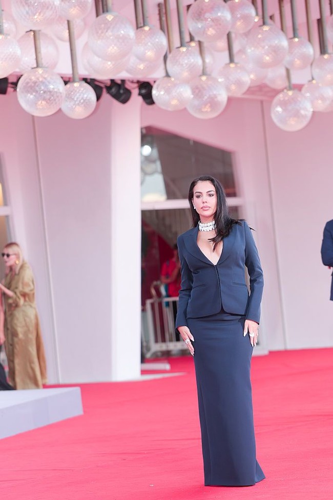 Wanita 32 tahun ini mengenakan setelan rok berwarna navy yang terdiri dari blazer berpotongan tailored dengan detail garis leher rendah yang mengekspos dada. Foto: FilmMagic/Jacopo Raule