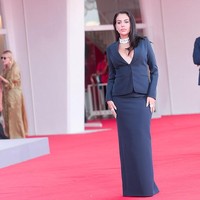 Wanita 32 tahun ini mengenakan setelan rok berwarna navy yang terdiri dari blazer berpotongan tailored dengan detail garis leher rendah yang mengekspos dada. Foto: FilmMagic/Jacopo Raule