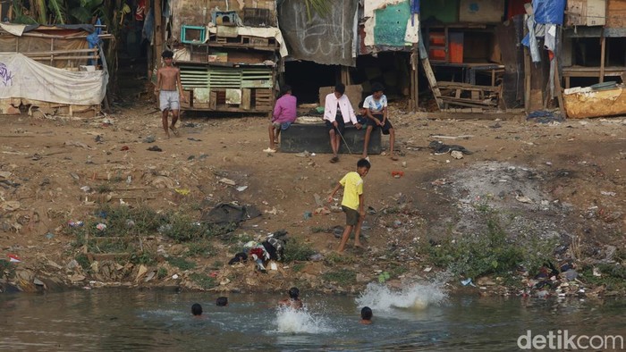 Anak-anak bermain di depan gedung semi permanen di Tanah Abang, pinggiran Sungai Banjir Kanal Barat (BKB), Jakarta, Sabtu (5/9/2026), dengan deretan gedung pencakar langit terlihat di belakangnya.