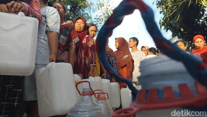 Warga Blitar membawa air bersih saat dropping air dari pemerintah