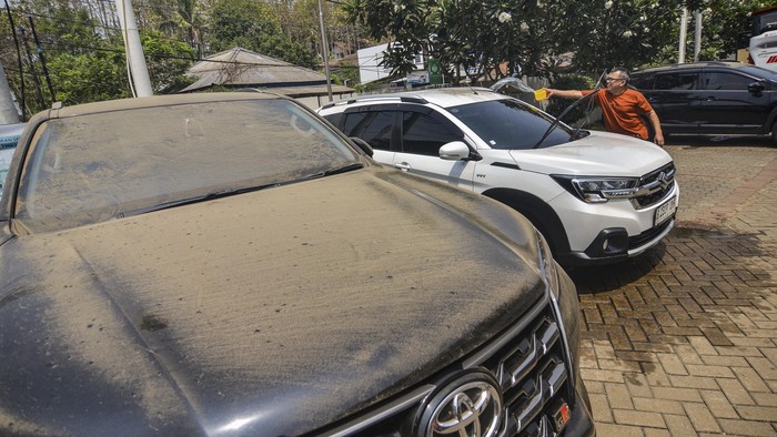 A man clears volcanic ash from his car following the eruption of Mount Anak Krakatoa in Serang on September 6, 2026. Mount Anak Krakatoa erupted on September 5, producing a fountain of lava and booming sounds that could be heard up to 700 kilometres (435 miles) away. (Photo by RONALD Siagian / AFP)
