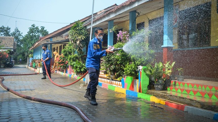 Penjaga sekolah membersihkan lantai dari abu vulkanik Gunung Anak Krakatau di SMP Negeri 1 Kalianda, Kabupaten Lampung Selatan, Lampung, Senin (7/9/2026). Pembersihan dilakukan untuk mencegah penumpukan abu vulkanik dan mempersiapkan sekolah jika pembelajaran tatap muka kembali digelar. ANTARA FOTO/Putra M. Akbar/tom.