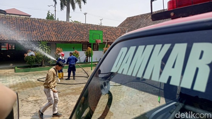 Petugas Damkar membersihkan sisa debu vulkanik di sekolah.