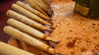  Sejumlah canting tradisional berbahan tembaga dengan gagang bambu tersusun rapi di atas wajan kecil berisi malam cair yang dipanaskan menggunakan kompor listrik. 