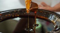  Malam atau lilin batik tampak meleleh sempurna, siap digunakan untuk proses membatik di atas kain. Ujung canting yang berbentuk corong kecil dicelupkan ke dalam wajan berisi malam panas sebelum digoreskan ke kain. 