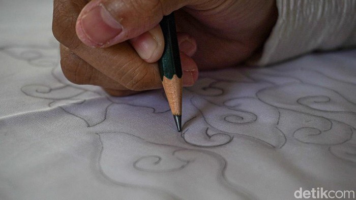 Pengunjung Museum Batik TMII belajar membatik dengan canting tradisional, menggoreskan malam panas mengikuti pola motif megamendung di atas kain.