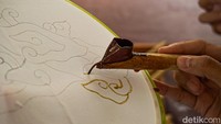 Kain yang telah diberi pola kemudian dipasang pada bingkai atau pemidangan berwarna hijau agar permukaannya tetap kencang saat dibatik. Peserta tampak menggoreskan canting berisi malam panas mengikuti pola pensil yang telah digambar sebelumnya. 