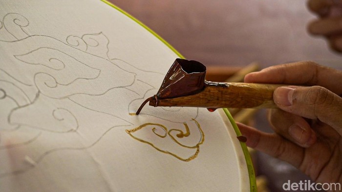 Pengunjung Museum Batik TMII belajar membatik dengan canting tradisional, menggoreskan malam panas mengikuti pola motif megamendung di atas kain.