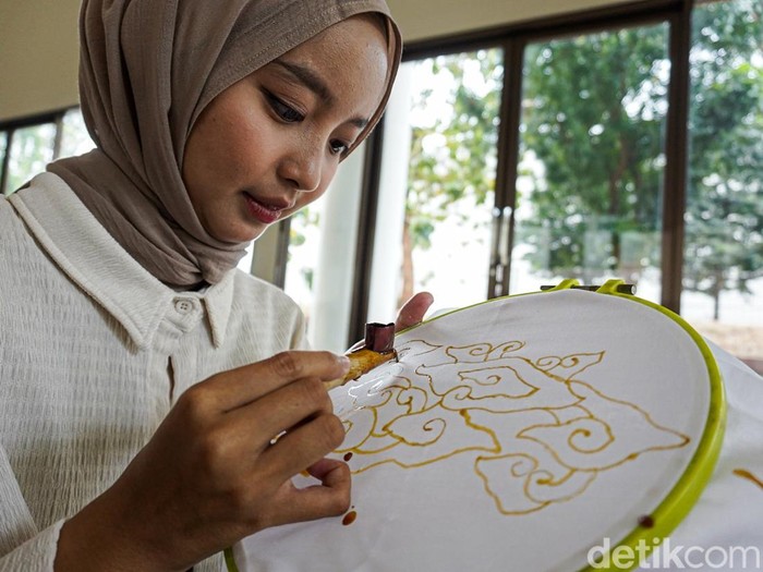 Pengunjung Museum Batik TMII belajar membatik dengan canting tradisional, menggoreskan malam panas mengikuti pola motif megamendung di atas kain.
