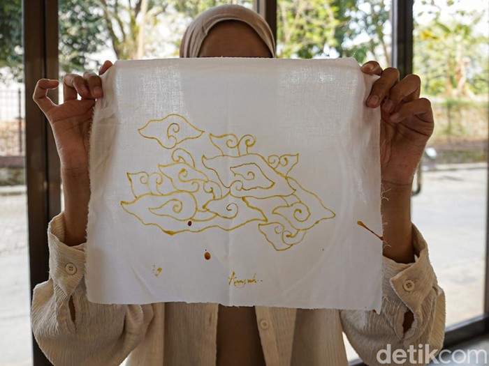 Pengunjung Museum Batik TMII belajar membatik dengan canting tradisional, menggoreskan malam panas mengikuti pola motif megamendung di atas kain.
