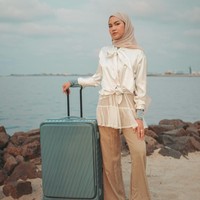Xaviera Putri memakai pashmina segi empat nude bernuansa earth tone yang dililit rapi ke belakang. Outfit memadukan blouse putih aksen pita dengan luaran tulle transparan serta celana bahan high-waist berwarna krem netral yang elegan. Foto: Dok. Instagram @xavieraaputri.