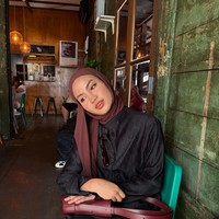 Kali ini, Xaviera menggunakan pashmina cokelat tua bernuansa bold yang salah satu sisinya dibiarkan menjuntai ke depan. Padu padan outfit berupa atasan hitam textured dan rok senada yang dilengkapi tas bahu merah bata untuk memberi aksen warna matching. Foto: Dok. Instagram @xavieraaputri.