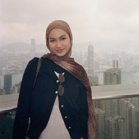 Gaya hijab memakai pashmina bermotif abstrak ala gen z, bernuansa cokelat hangat yang disampirkan santai di bahu. Padu padan outfit bergaya kasual elegan dengan memadukan cardigan hitam berdetail kancing emas dan dalaman putih. Foto: Dok. Instagram @xavieraaputri.