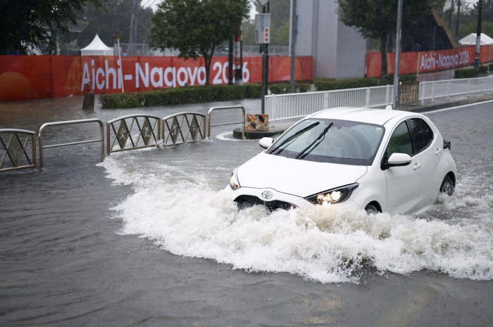 A car drives along a road flooded by heavy rain while banners for the Aichi-Nagoya Asian Games are visible in the background in Nagoya, central Japan September 8, 2026, in this photo taken by Kyodo. Mandatory credit Kyodo/via REUTERS ATTENTION EDITOR