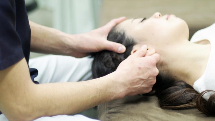 Woman receiving massage in ear in Japan