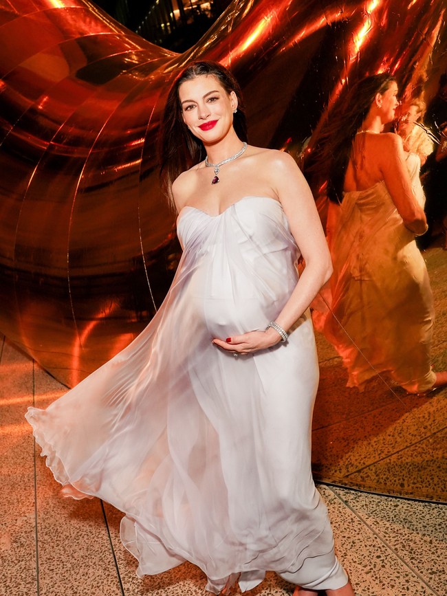 Anne Hathaway tampil anggun dalam gaun maxi berbahan silk warna lilac lembut dari Alexander McQueen. Gaun strapless tersebut memiliki detail kerutan pada bagian dada dan siluet longgar yang jatuh mengikuti bentuk tubuh serta baby bump-nya. Foto: Instagram/@bvlgari