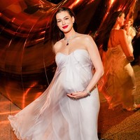 Anne Hathaway tampil anggun dalam gaun maxi berbahan silk warna lilac lembut dari Alexander McQueen. Gaun strapless tersebut memiliki detail kerutan pada bagian dada dan siluet longgar yang jatuh mengikuti bentuk tubuh serta baby bump-nya. Foto: Instagram/@bvlgari