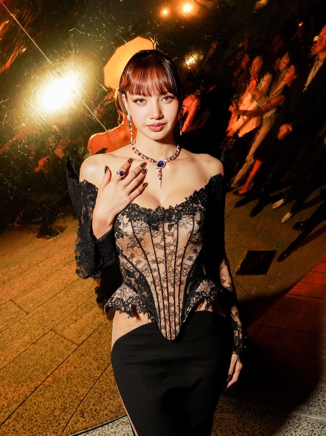 Lisa BLACKPINK membawa gaya lebih dramatis lewat gaun hitam dengan belahan tinggi hingga paha. Bagian atasnya memiliki struktur korset dengan panel lace bermotif floral, memberi nuansa lingerie-inspired. Sementara itu, garis leher off-shoulder menambahkan kesan sensual pada keseluruhan penampilan. Foto: Instagram/@bvlgari