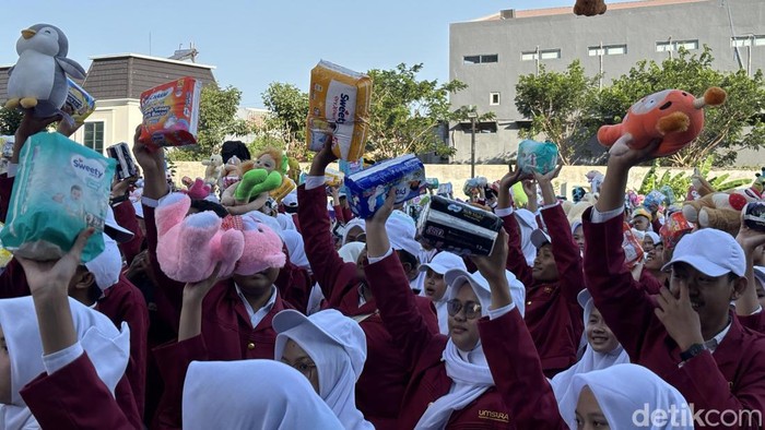 Aksi ribuan maba Umsura mengangkat boneka, pembalut dan boneka bentuk kepedulian korban bencana anak dan perempuan NTT
