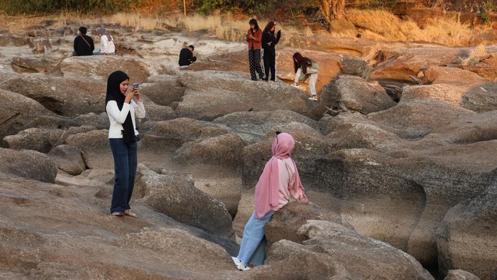 Warga berfoto di area aliran Sungai Jeneberang yang mengering di Kabupaten Gowa, Sulawesi Selatan, Minggu (13/9/2026). Area dasar sungai yang mengering akibat penurunan debit air di tengah musim kemarau dan penguatan fenomena El Nino tersebut dimanfa