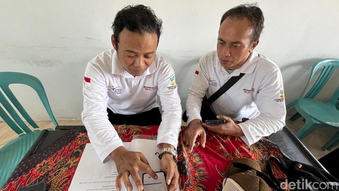 Pendamping PKH Kecamatan Genteng memeriksa data penerima Bansos lewat perangkat handphone