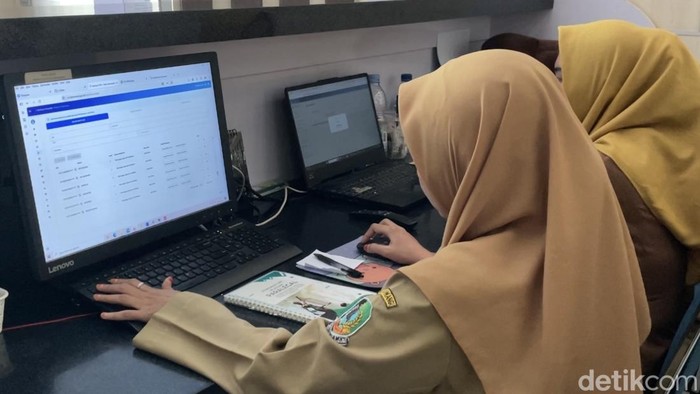 Petugas Dinsos tengah mengecek data penerima Bansos di depan komputer.