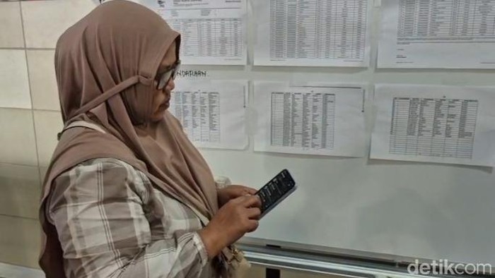 Anita Margi Utami menunjukkan tiket keberangkatan hingga foto suaminya, Agus Ribut Setio.