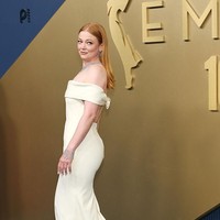 Sarah Snook memberikan gaya elegan dengan gaun putih off-shoulder dari Balenciaga. Gaun tersebut memiliki detail pita besar di bagian belakang yang menjadi aksen manis sekaligus dramatis pada penampilannya di Emmy Awards 2026. (Foto: Getty Images/Monica Schipper)