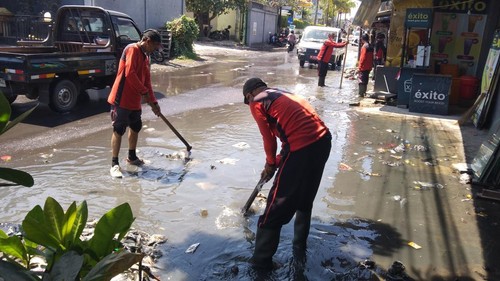 Petugas Dinas PUPR Tabanan menangani luapan air irigasi di Jalan Jepun, Banjar Tegal Belodan, Desa Dauh Peken, tepatnya di depan Rumah Sakit (RS) Kasih Ibu Tabanan, Selasa (15/9/2026) siang. (Krisna Pradipta/detikBali)