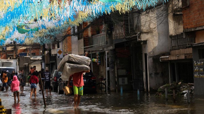 A residents carries matresses and belongings away from the water in the flooded streets in the Jardim Pantanal neighborhood following heavy rains in Sao Paulo, Brazil, September 15, 2026. REUTERS/Tuane Fernandes