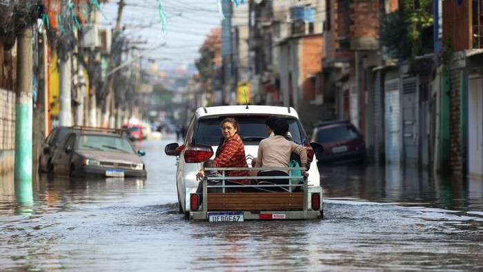 Banjir Landa Sao Paulo Brasil, 110 Keluarga Mengungsi A residents carries matresses and belongings away from the water in the flooded streets in the Jardim Pantanal neighborhood following heavy rains in Sao Paulo, Brazil, September 15, 2026. REUTERS/Tuane Fernandes
