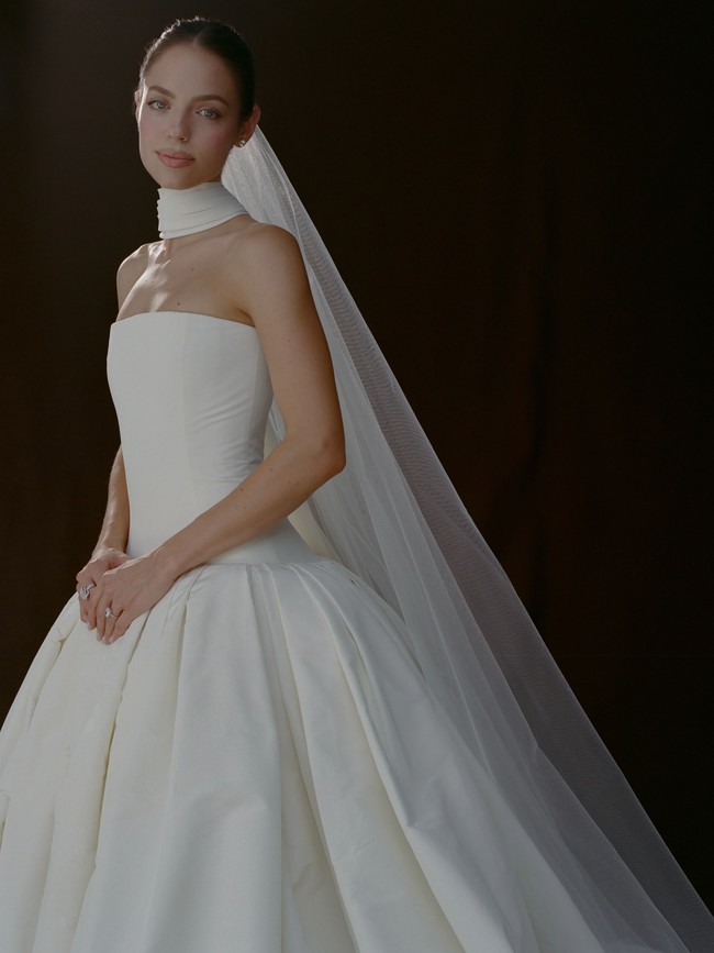 Seperti dikutip dari Vogue, gaun pengantin utama Claudia untuk upacara pernikahan berupa ball gown berbahan silk faille warna ivory dengan bagian dada model drop-waist dan rok berlipat yang terstruktur, dihiasi selendang leher asimetris yang menjuntai sepanjang ekor gaun. Foto: Dok. Instagram VogueWedding, Claudia Sulewski