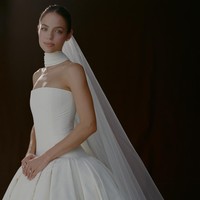 Seperti dikutip dari Vogue, gaun pengantin utama Claudia untuk upacara pernikahan berupa ball gown berbahan silk faille warna ivory dengan bagian dada model drop-waist dan rok berlipat yang terstruktur, dihiasi selendang leher asimetris yang menjuntai sepanjang ekor gaun. Foto: Dok. Instagram VogueWedding, Claudia Sulewski