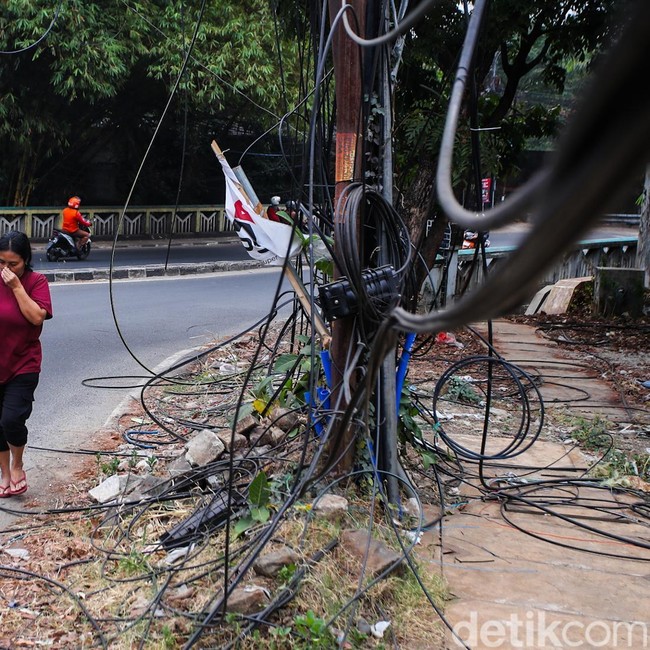 Semrawut! Kabel Fiber Optik Bergelantungan di Jalan Raya Cirendeu